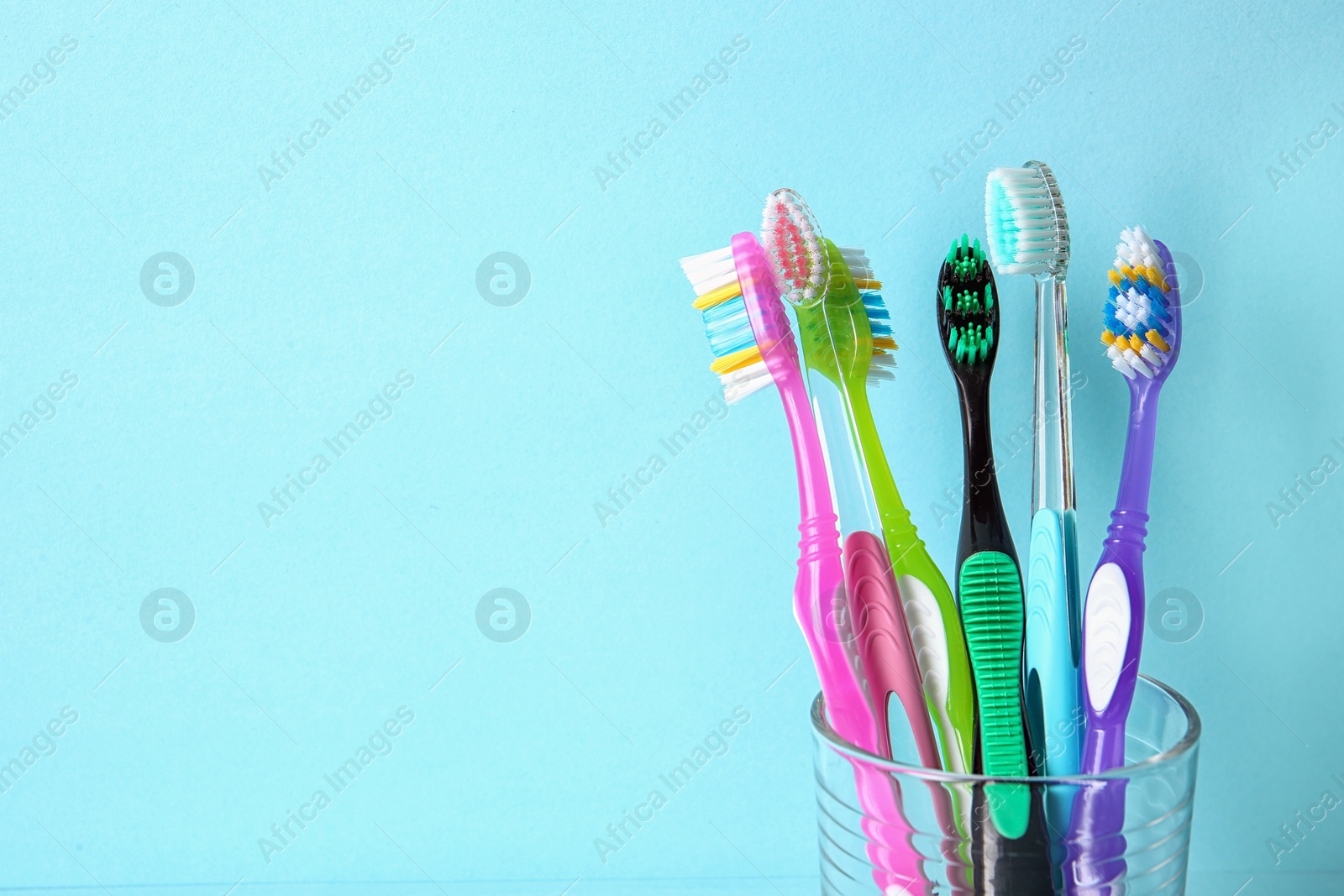 Photo of Cup with toothbrushes against color background. Dental care