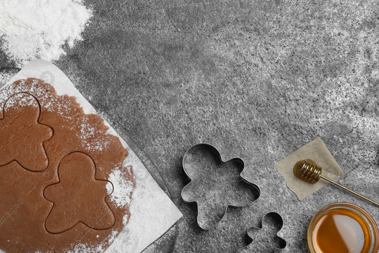 Photo of Flat lay composition with homemade gingerbread man cookies on grey table, space for text