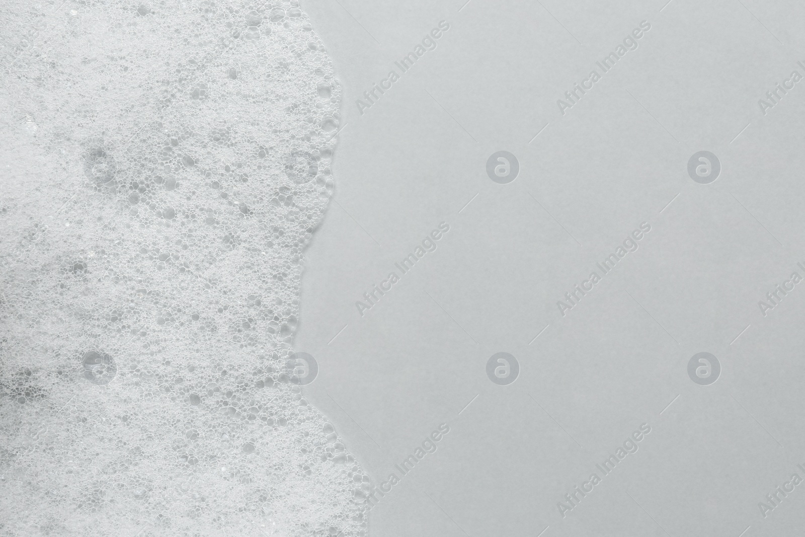 Photo of Fluffy bath foam on light background, top view. Space for text