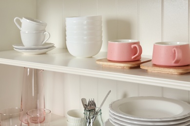 Photo of White shelving unit with set of dishware