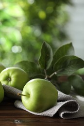 Photo of Fresh ripe green apples and leaves on wooden table outdoors