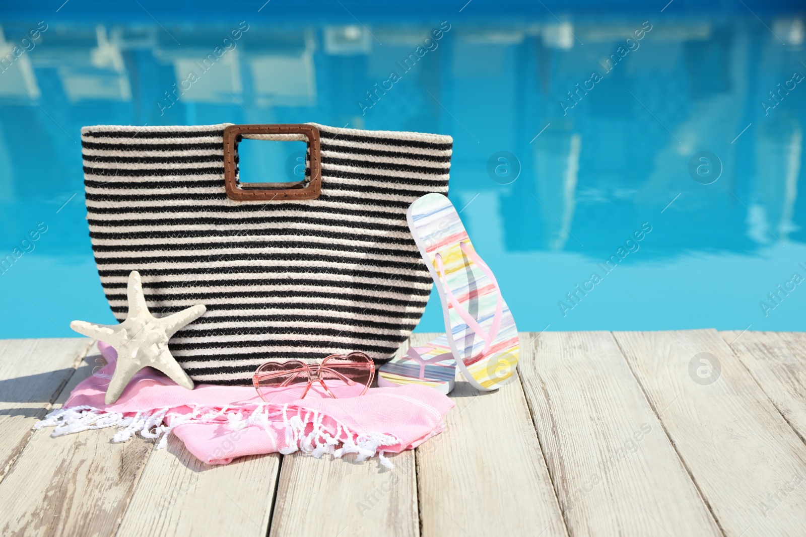 Photo of Beach accessories on wooden deck near outdoor swimming pool, space for text