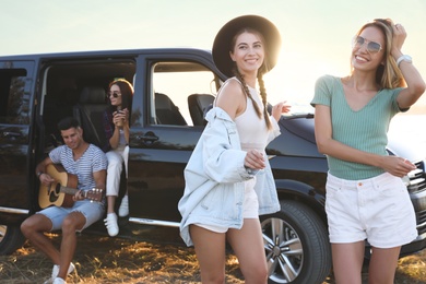 Photo of Happy friends having fun near car outdoors. Summer trip