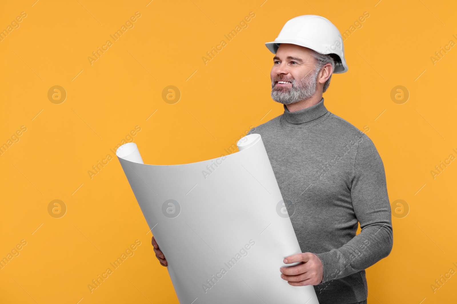 Photo of Architect in hard hat holding draft on orange background