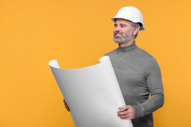 Photo of Architect in hard hat holding draft on orange background