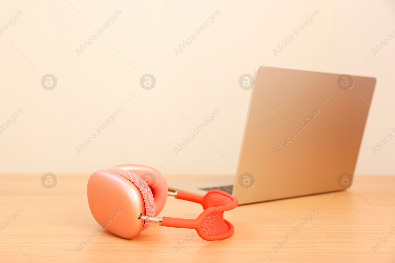 Photo of Modern headphones and laptop on wooden table. Space for text