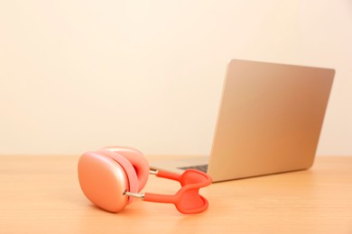 Modern headphones and laptop on wooden table. Space for text