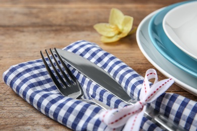 Cutlery set and dishware on wooden table, closeup