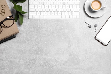 Flat lay composition with computer keyboard and smartphone on grey table. Space for text