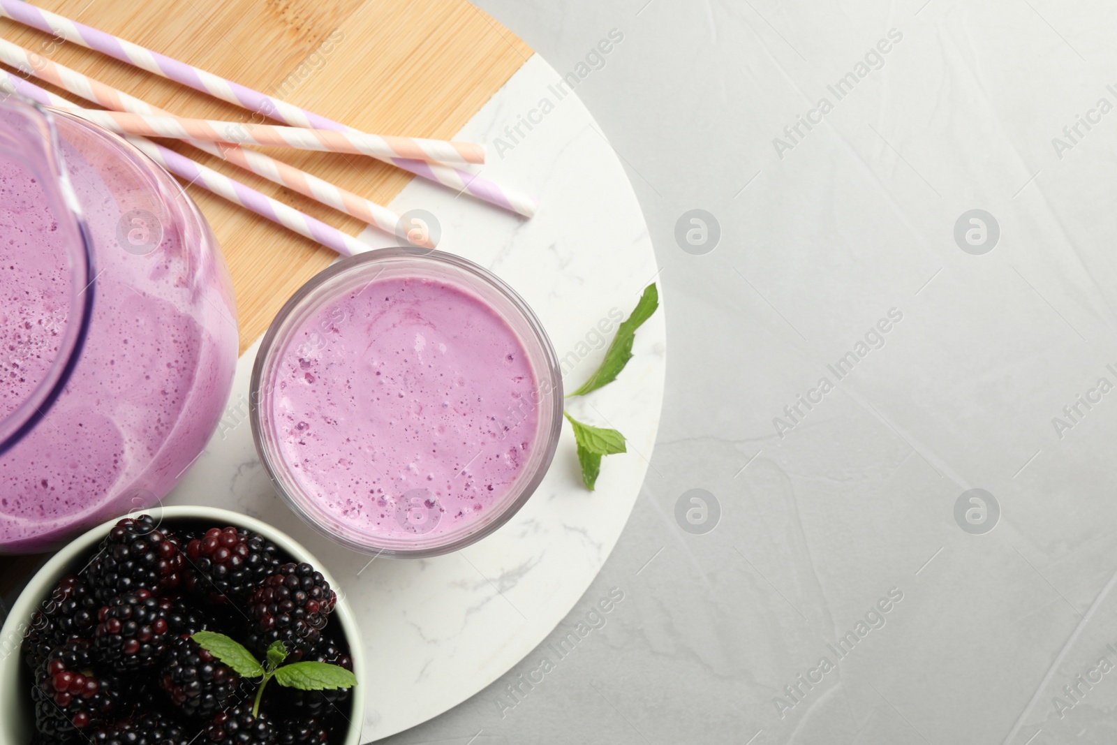 Photo of Delicious blackberry smoothie and berries on white table, top view. Space for text