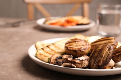 Photo of Delicious grilled vegetables and mushrooms served on grey table, closeup