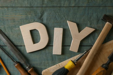 Photo of Abbreviation DIY made of letters and different tools on grey wooden table, flat lay