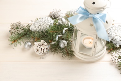 Photo of Christmas lantern with burning candle and festive decor on white wooden table