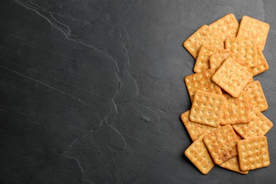 Many delicious crackers on black table, flat lay. Space for text