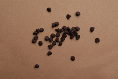 Pile of delicious chocolate chips on brown background, top view