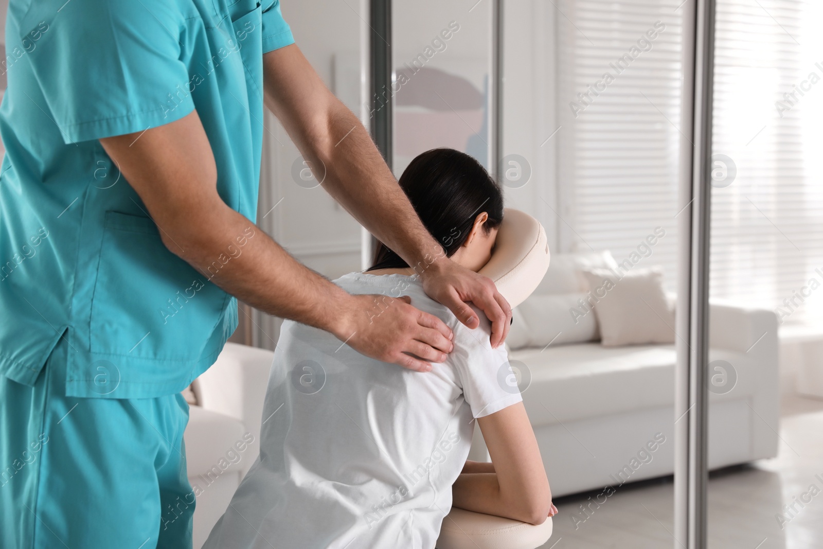 Photo of Woman receiving massage in modern chair indoors