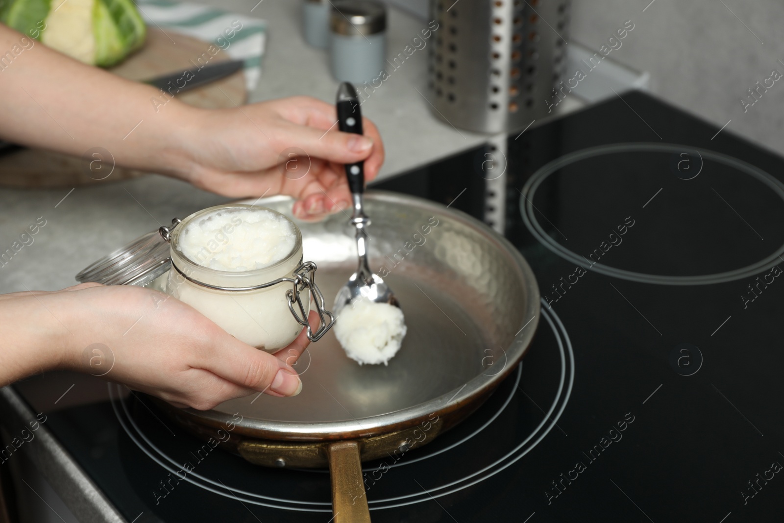 Photo of Woman cooking with coconut oil on induction stove, closeup