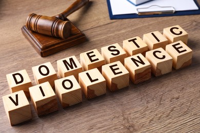 Photo of Wooden cubes with words DOMESTIC VIOLENCE on wooden table
