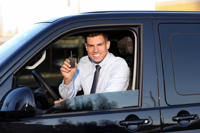 Photo of Man with key sitting in car outdoors. Buying new auto