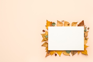 Flat lay composition with autumn leaves and blank card on light background, space for text