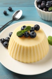 Photo of Delicious semolina pudding with blueberries on light blue wooden table