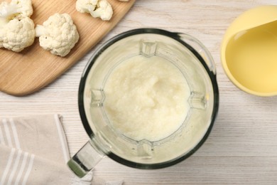 Photo of Baby food. Blender with delicious cauliflower puree on light wooden table, flat lay