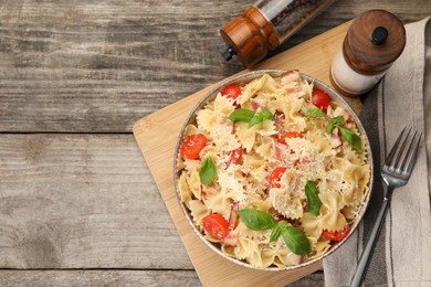 Photo of Delicious pasta with tomatoes, basil and parmesan cheese served on wooden table, flat lay. Space for text