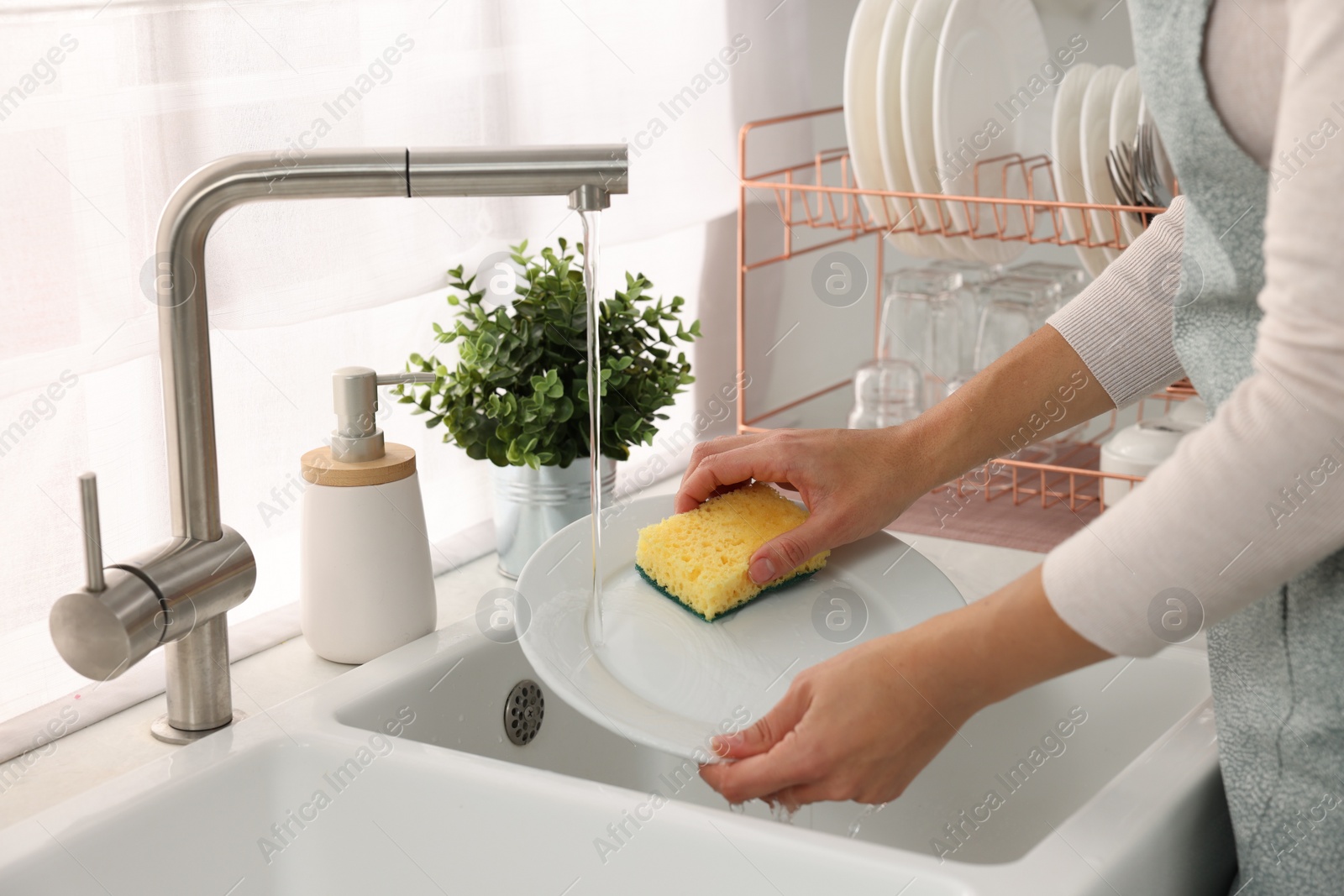 Photo of Woman washing plate at sink in kitchen, closeup