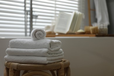Wooden tray with spa products and book on bath tub in bathroom, selective focus