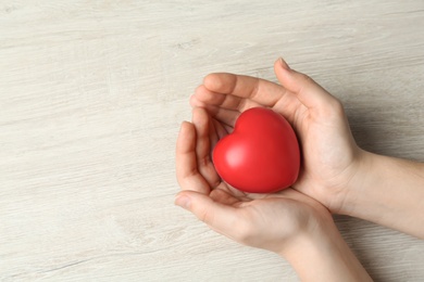 Photo of Woman holding red heart on wooden background, above view with space for text. Happy Valentine's Day