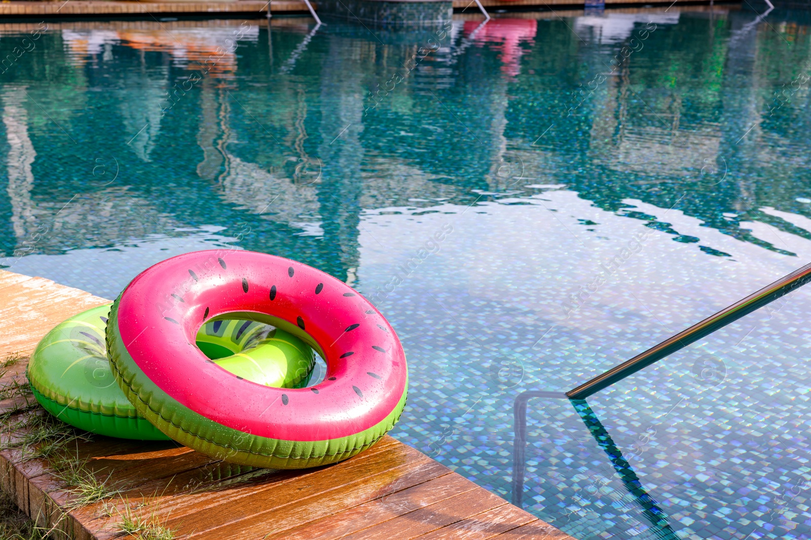 Photo of Inflatable rings on wooden deck near swimming pool. Luxury resort