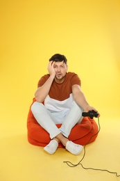 Photo of Emotional man playing video games with controller on color background