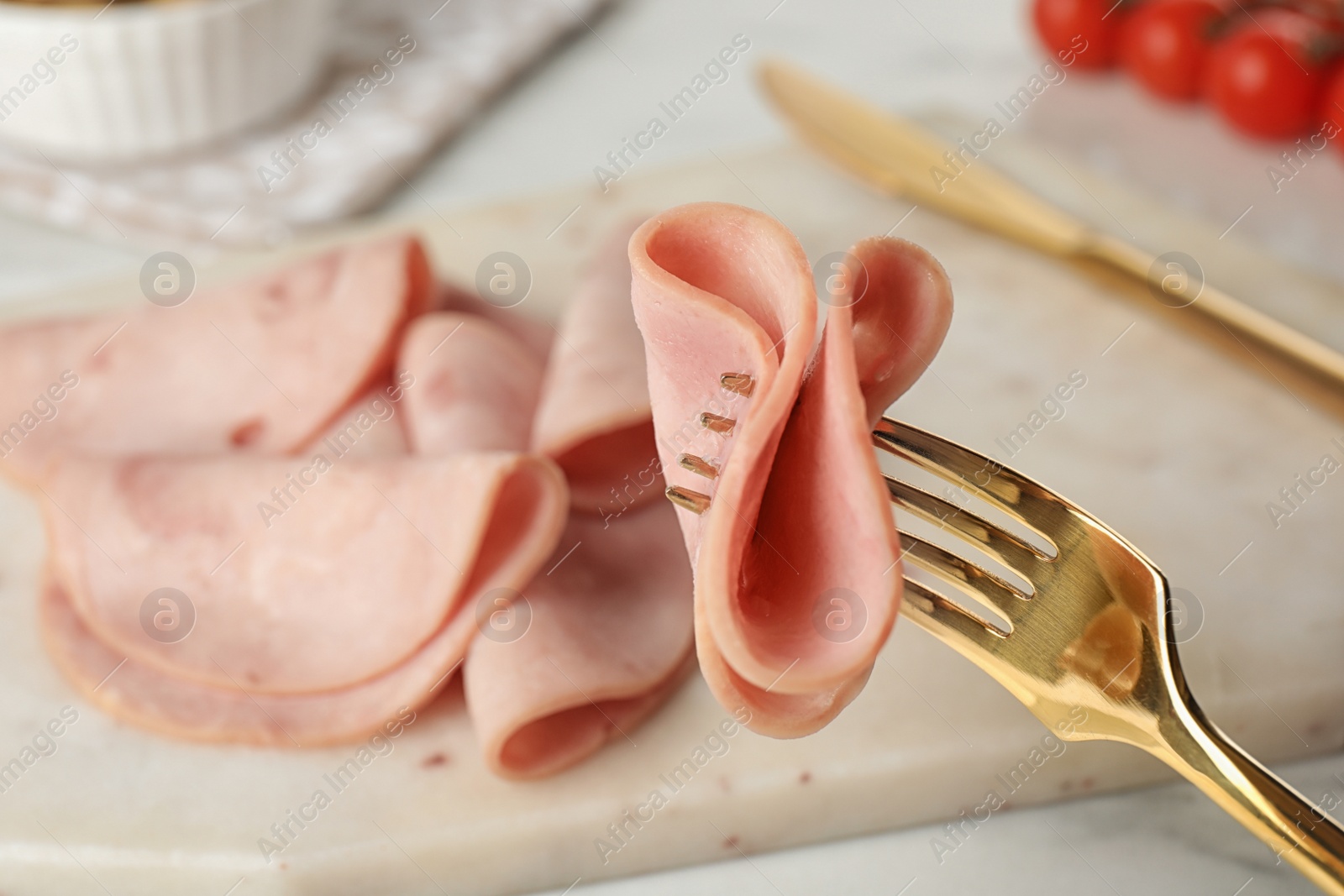 Photo of Fork with tasty ham over table, closeup