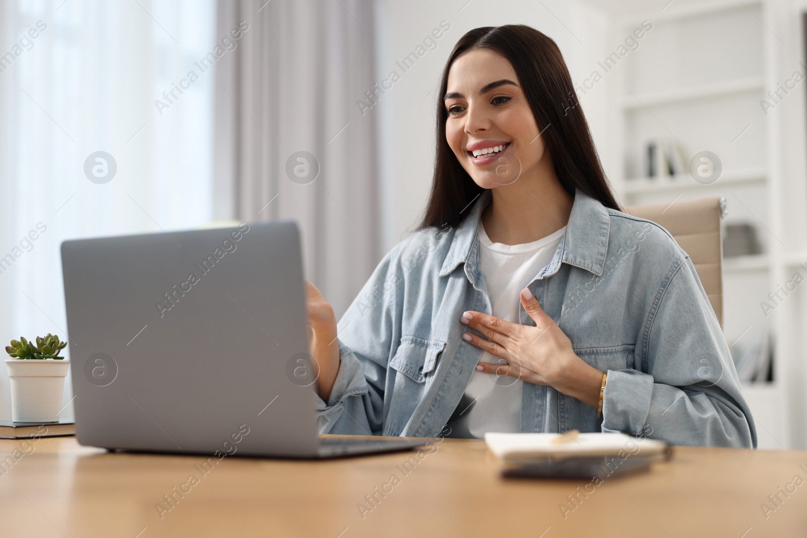 Photo of Young woman using video chat during webinar at table in room