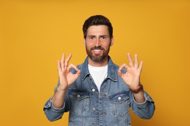 Bearded man doing ok gesture on orange background