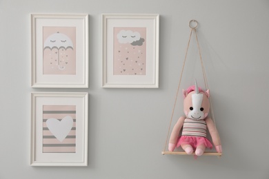 Different cute pictures on grey wall. Baby room interior