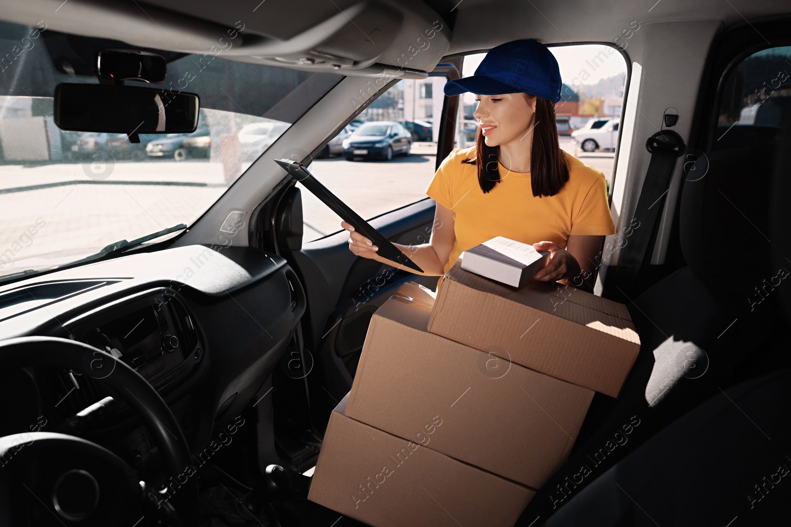 Photo of Courier with clipboard checking packages in car