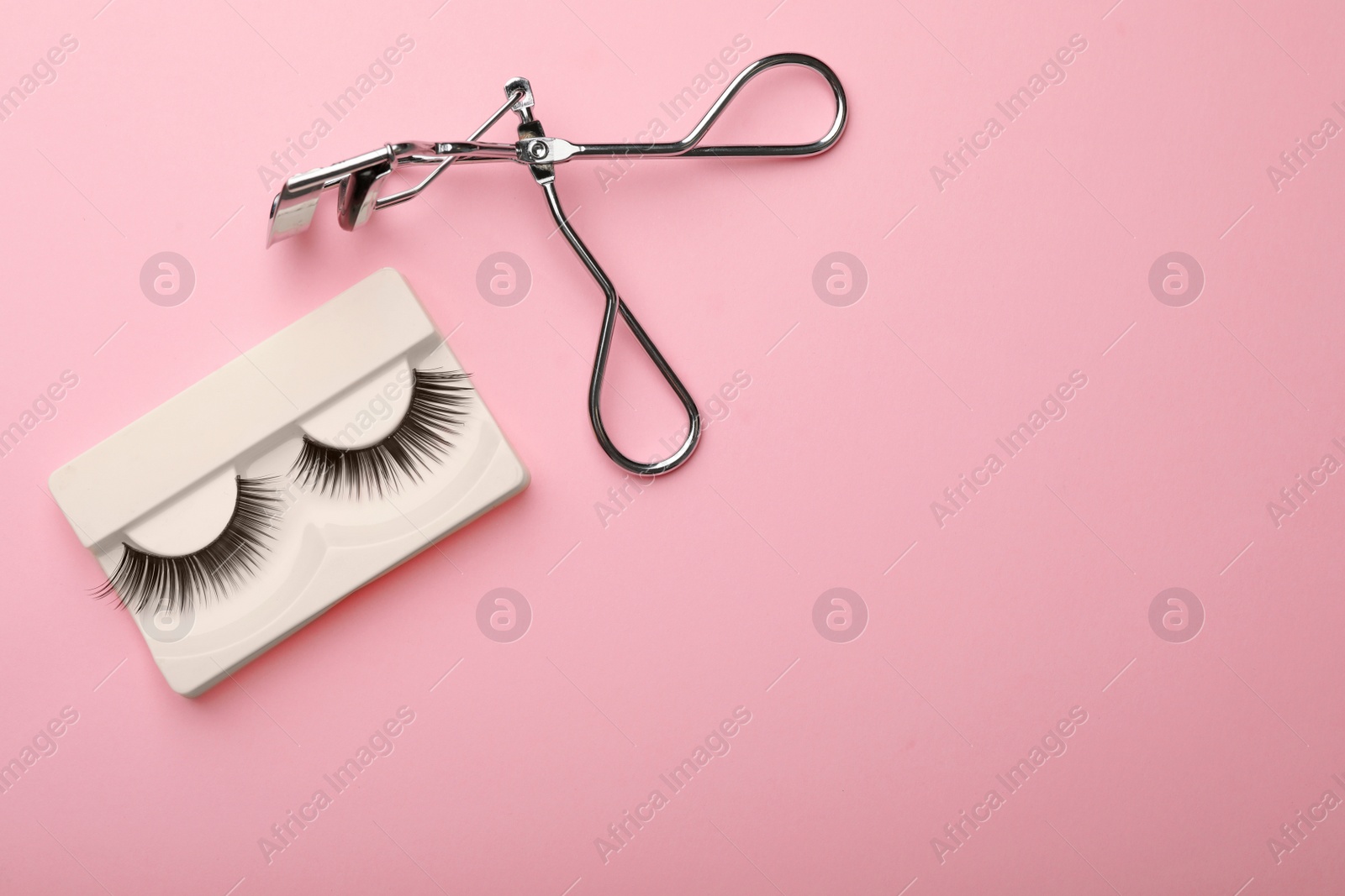 Photo of Flat lay composition of curler and false eyelashes on color background, space for text