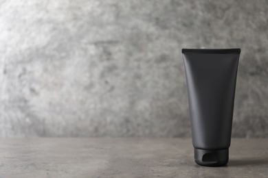 Tube of men's facial cream on grey stone table. Mockup for design