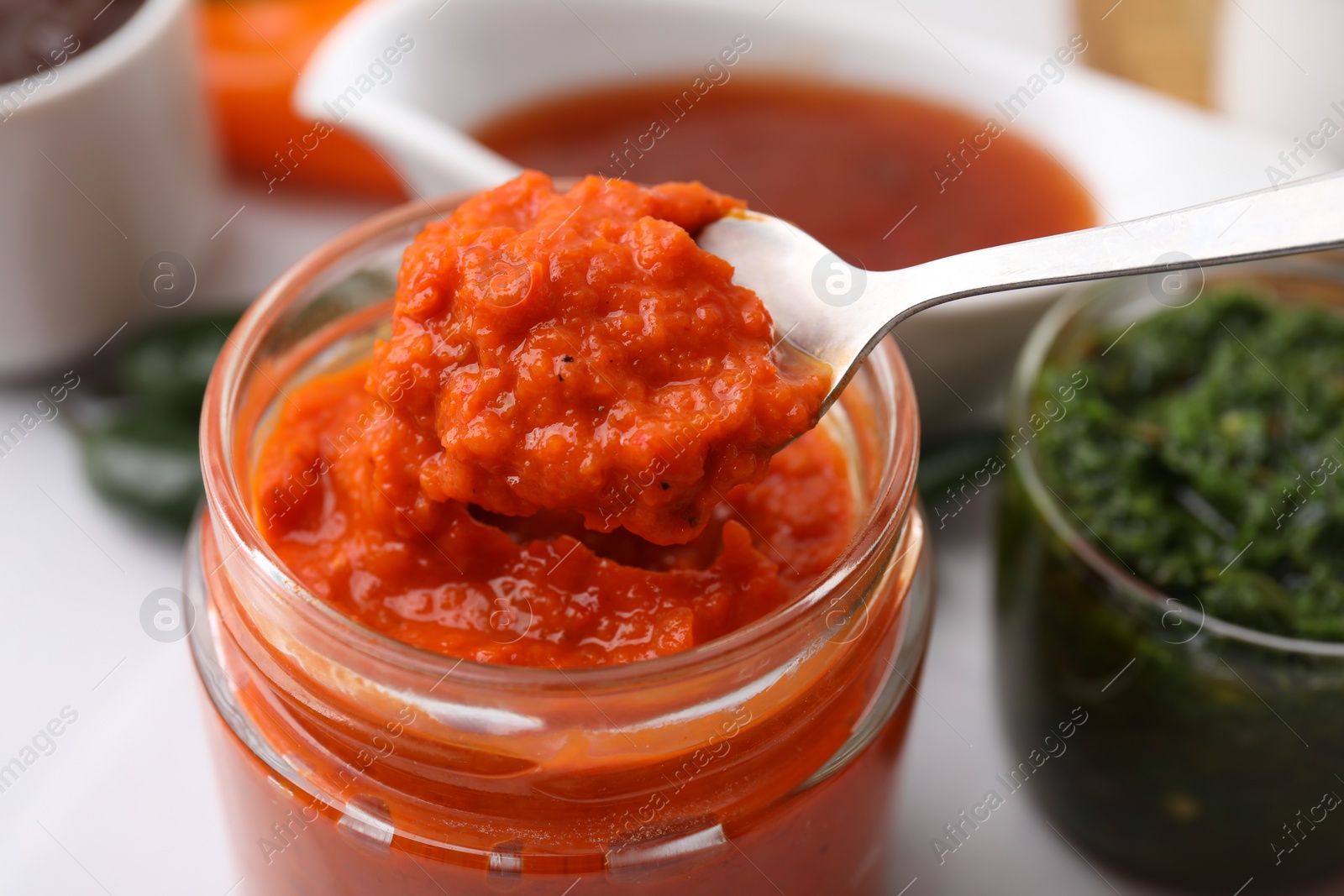 Photo of Taking homemade marinade from jar at table, closeup