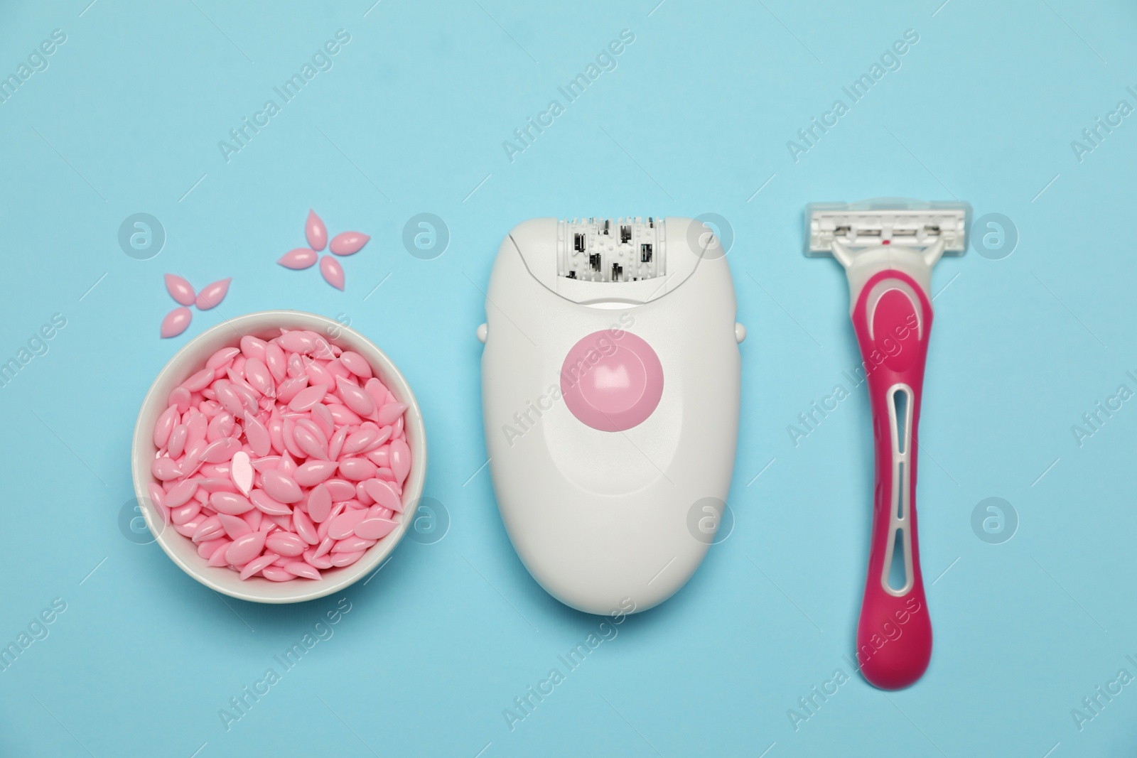 Photo of Epilator, razor and wax beads on light blue background, flat lay