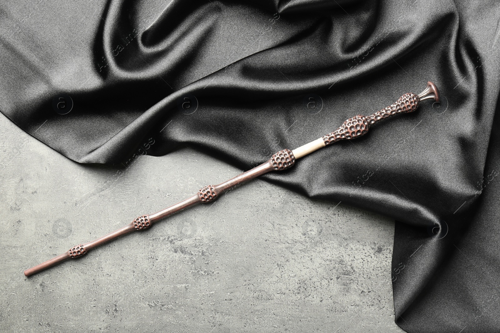 Photo of Magic wand and dark cloth on light grey background, top view