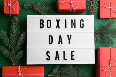 Lightbox with phrase BOXING DAY SALE and Christmas decorations on green background, flat lay