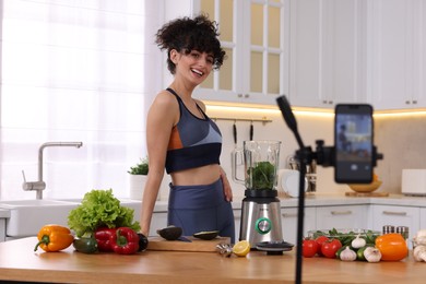 Smiling food blogger recording video in kitchen