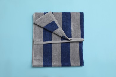 Folded striped beach towel on light blue background, top view