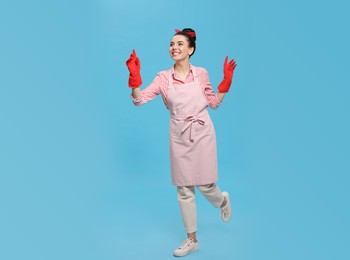 Photo of Housewife wearing rubber gloves on light blue background