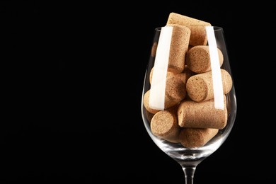 Photo of Glass full of wine corks on black background, closeup. Space for text