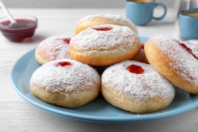 Photo of Delicious donuts with jam and powdered sugar on white table, closeup