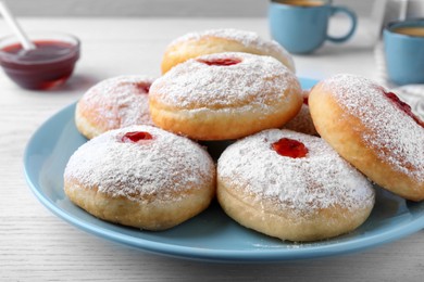 Delicious donuts with jam and powdered sugar on white table, closeup