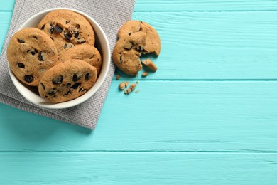 Photo of Bowl with many delicious chocolate chip cookies on turquoise wooden table, flat lay. Space for text